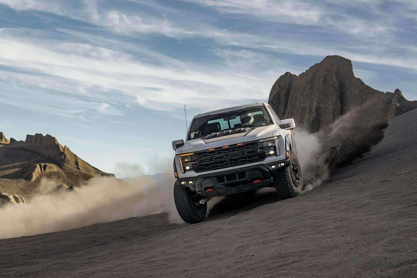 A gray 2025 Ford F-150 driving off-road and kicking up dirt