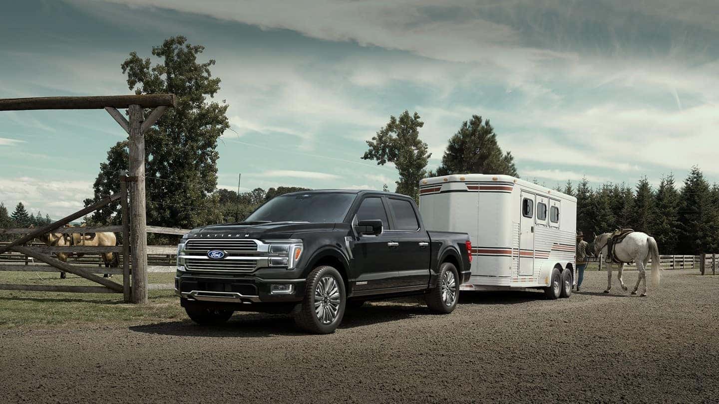 A black 2025 Ford F-150 hooked to a trailer on a farm or ranch