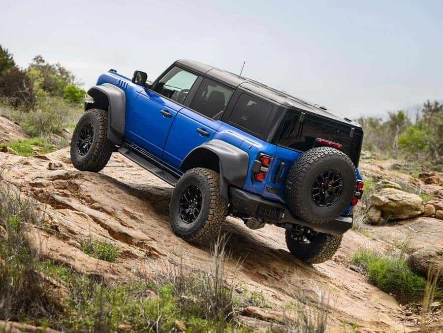 A blue 2025 Ford Bronco driving up a hill