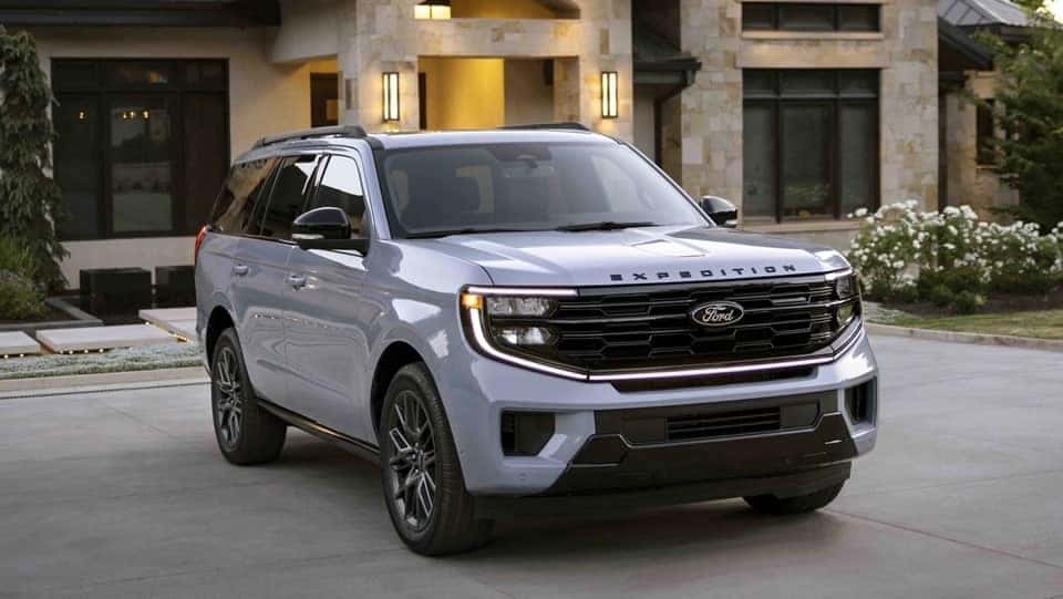 A silver 2025 Ford Expedition parked in front of a large house