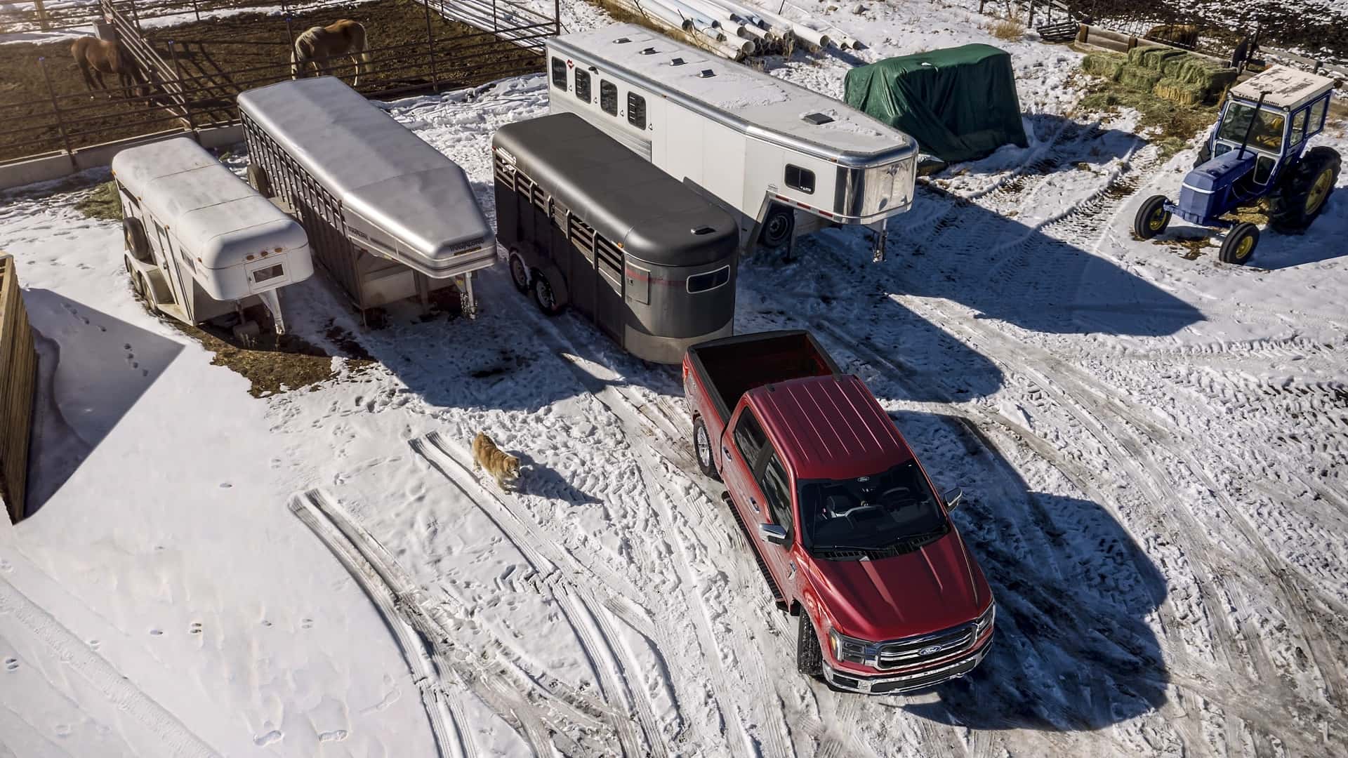 A red Ford F-150 backing up with a trailer in a snowy trailer park