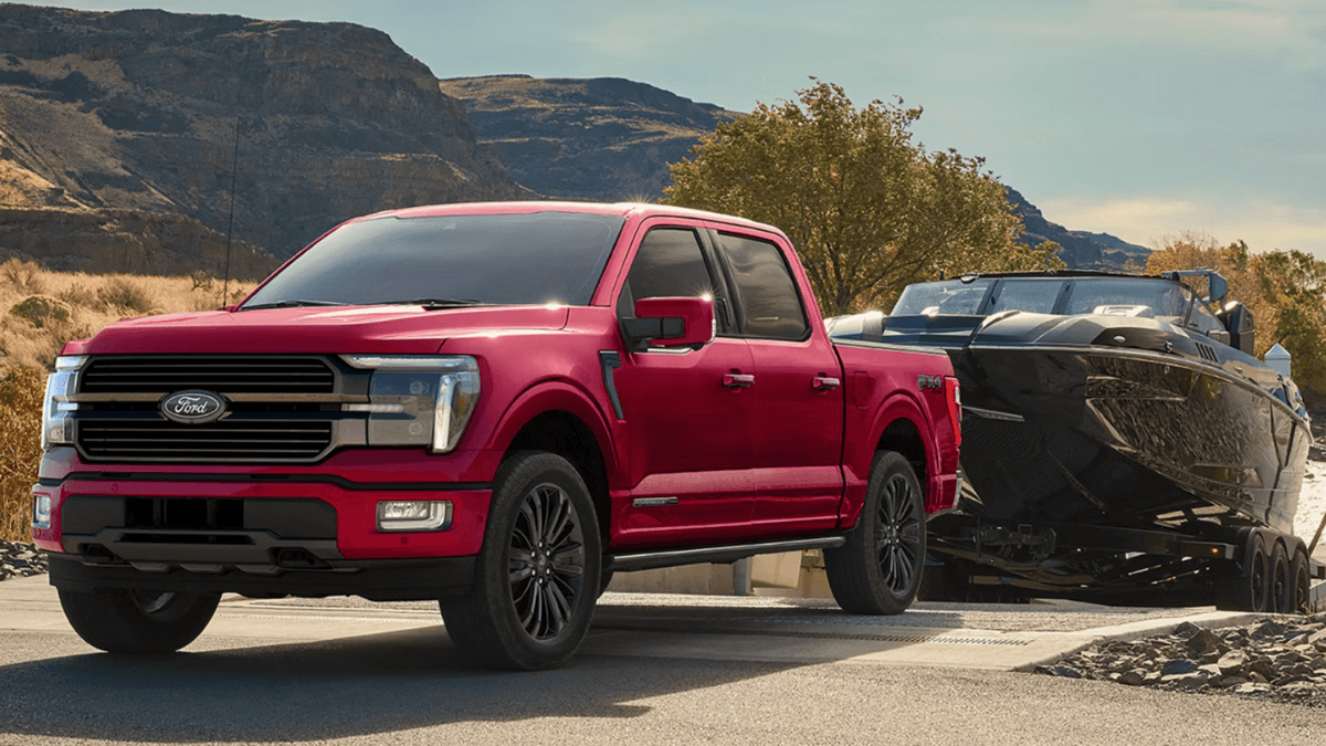 A red Ford F-150 hauling a boat into a lake