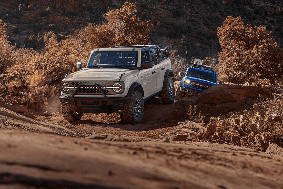 Two 2026 Ford Bronco SUVs off-roading on a dirt trail