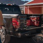 Rear view of the 2026 Ford F-150 with the truck bed open and a person next to it