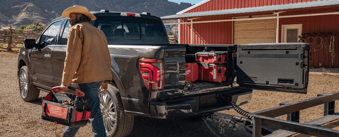 Rear view of the 2026 Ford F-150 with the truck bed open and a person next to it