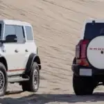 Two Ford Broncos side by side on sand dunes