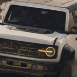 A white Ford Bronco kicking up dust as it drives off-road