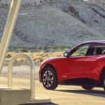 Red car parked on a road by electric charging pump