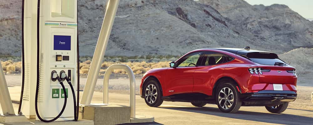 Red car parked on a road by electric charging pump
