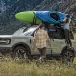 A couple of people standing next to a car with a kayak on top
