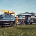 A person standing next to a car with a canoe on top