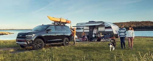 A person standing next to a car with a canoe on top