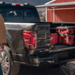 A person standing next to a truck with tool boxes in the back