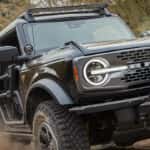 A black SUV driving on a dirt road