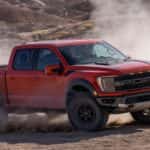 A red truck driving on a dirt road