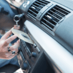 A vehicle dash with an arm inserting a CD into the CD player.