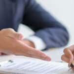Hand pointing to paperwork.