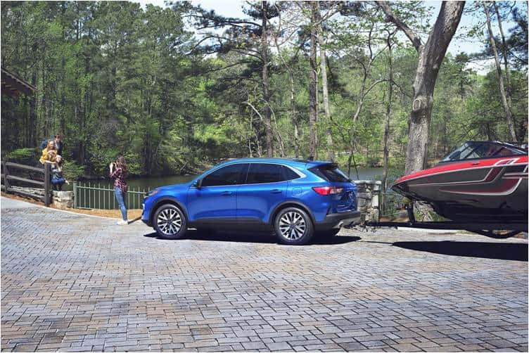 A blue car parked on a brick driveway next to a boat
