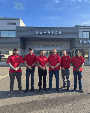 A group of men in red shirts standing in front of a service station