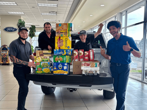 A group of men standing next to a truck with boxes of food