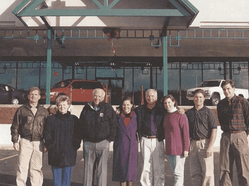 A 1995 group photo of the Wendle family and team standing in front of the newly built Nissan facility at the "Y" in Spokane.