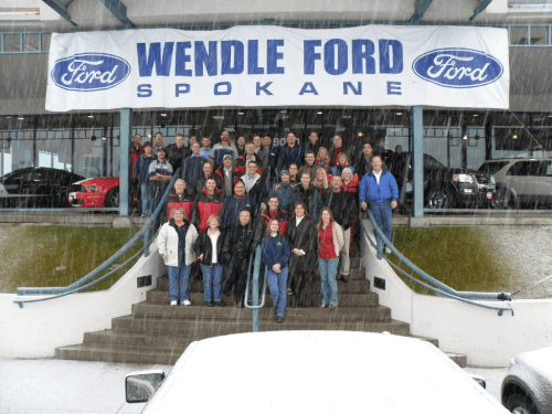 The Wendle Ford team posing on the entrance stairs of the new facility at the "Y" in 2008, under a large "Wendle Ford Spokane" banner.