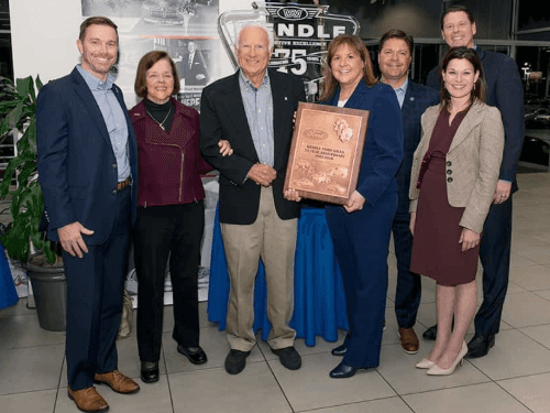 The Wendle family celebrating 75 years of Wendle Ford with a commemorative plaque in the dealership showroom.