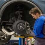 Ford service technician replacing the brake pad on a Ford SUV