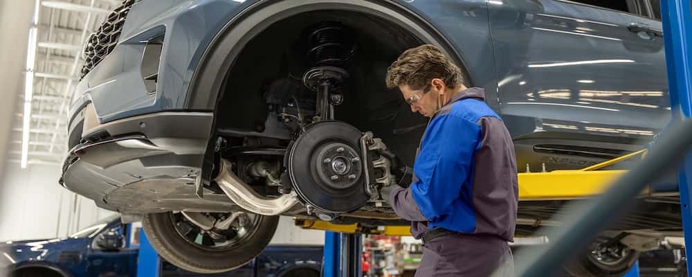 Ford service technician replacing the brake pad on a Ford SUV