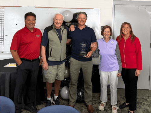 Five team members posing together indoors celebrating Kevin's 25th anniversary milestone award at Wendle Nissan.