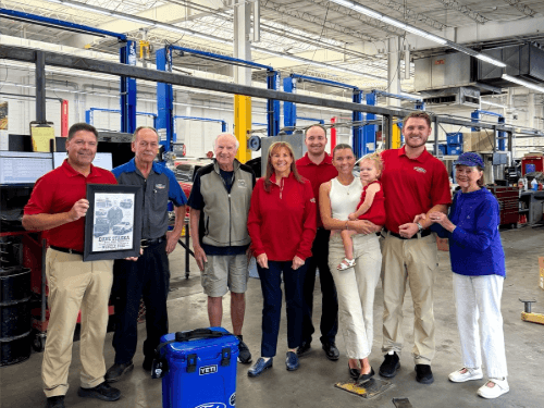 Wendle team members and family members posing together in the service department during Dave Staska's retirement celebration.
