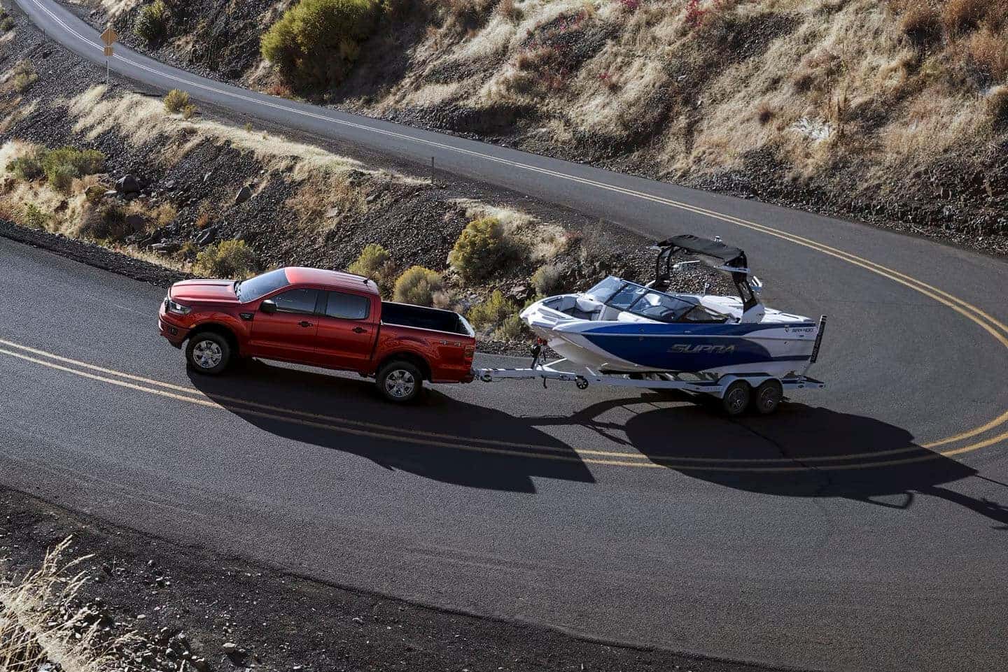 2023 Ford Ranger XLT towing a boat on a windy road.