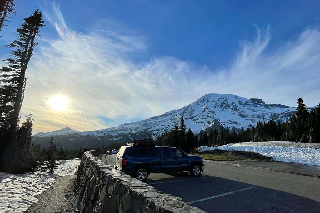 4x4 Pickup truck with a cover parked next to a snowy mountain