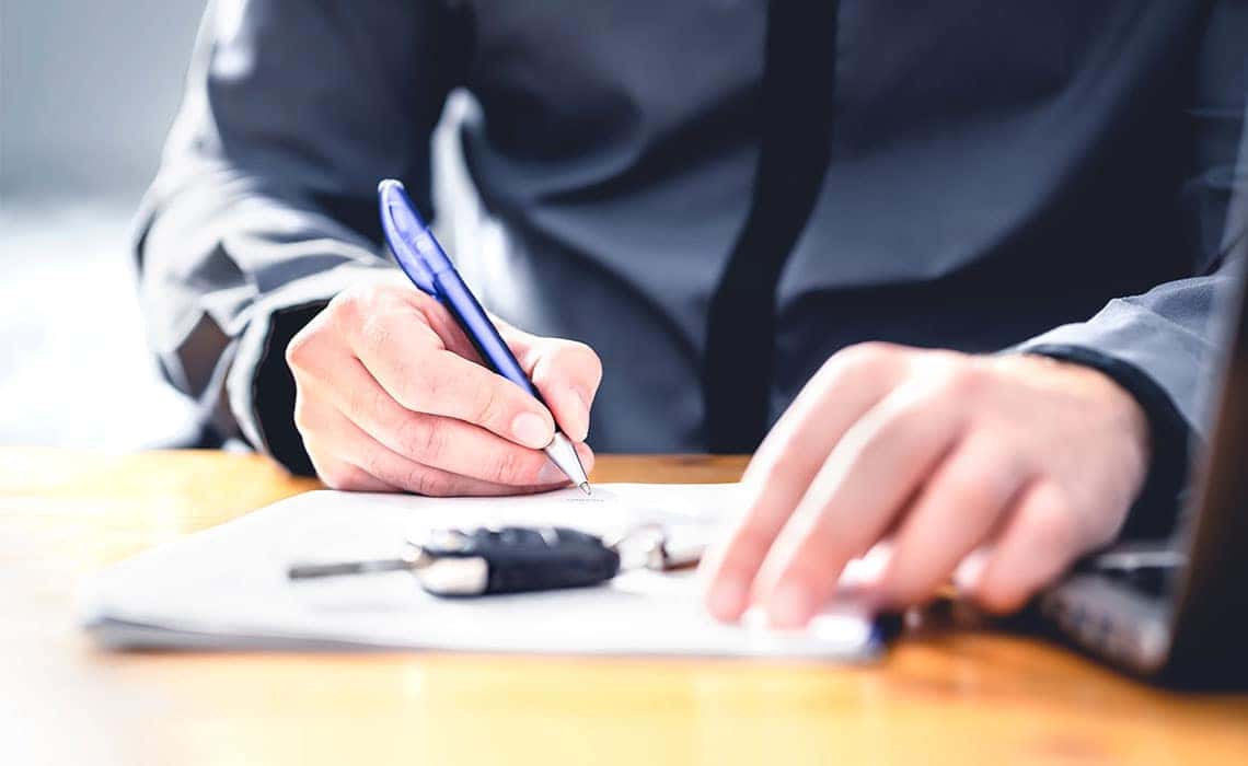 Person filling out finance paperwork at a car dealership