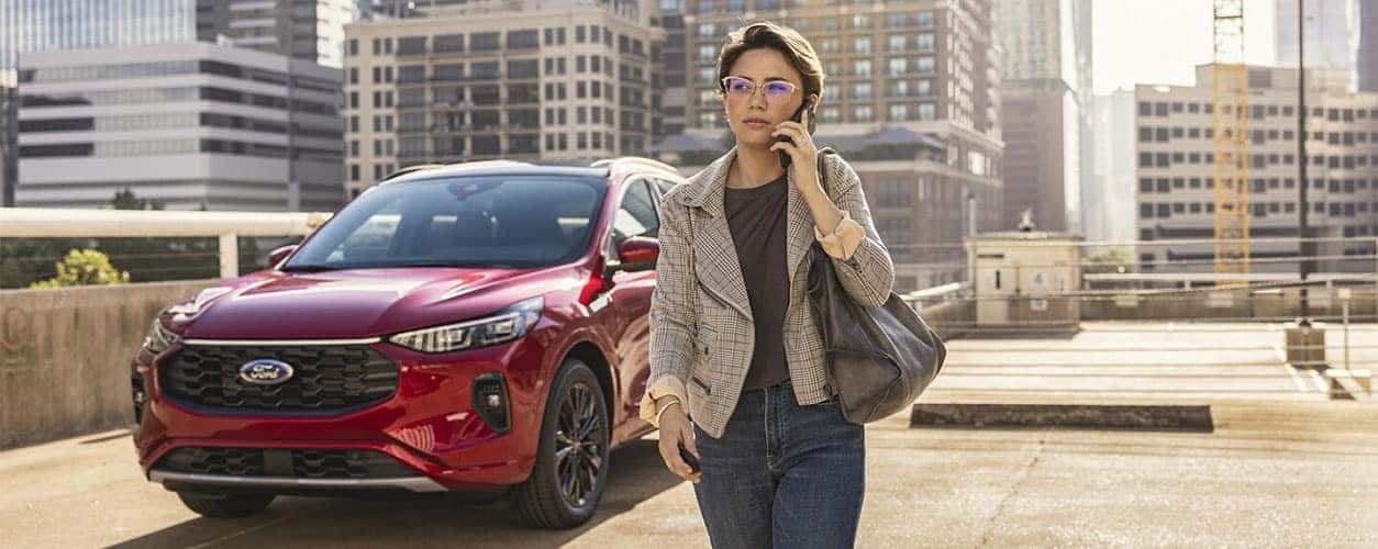 Woman on the phone walking away from a 2024 Ford Escape SUV in a parking lot
