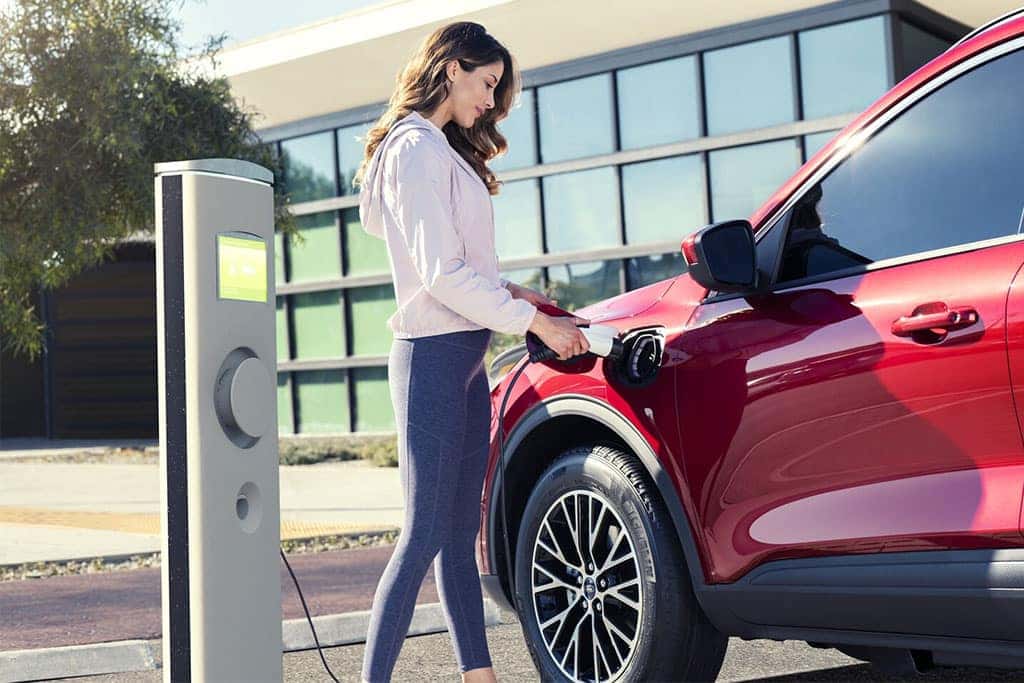 Woman charging a 2024 Ford Escape Plug-in Hybrid at a charging station
