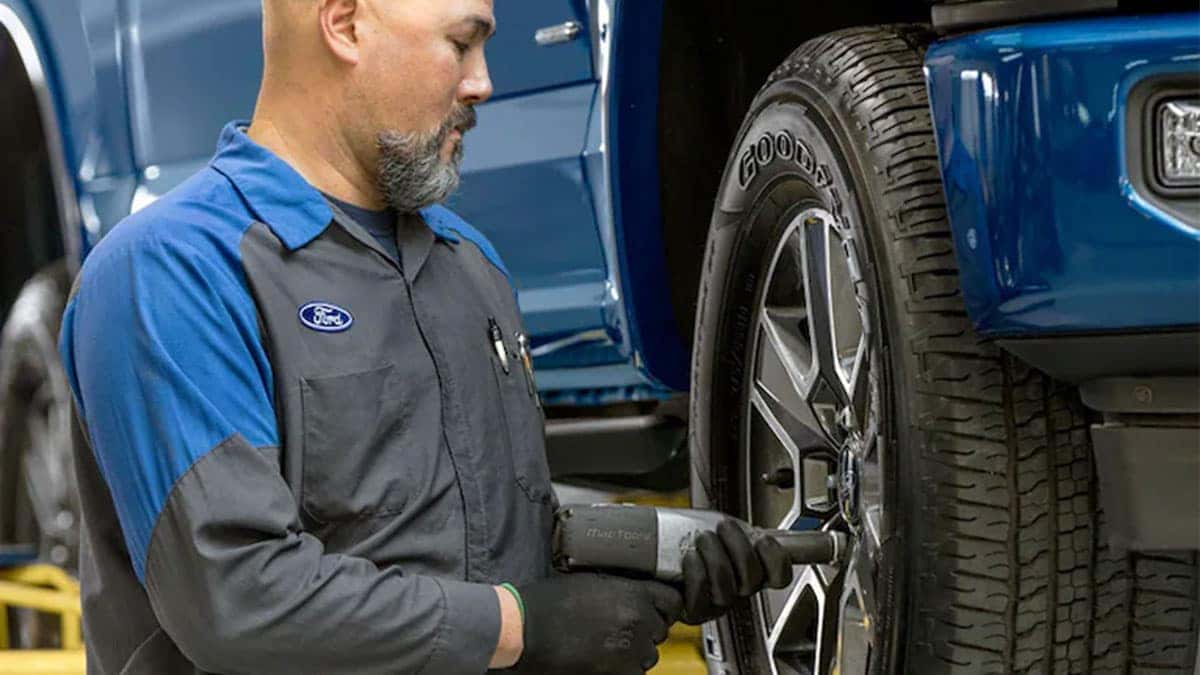 Ford service tech changing a tire on a Ford