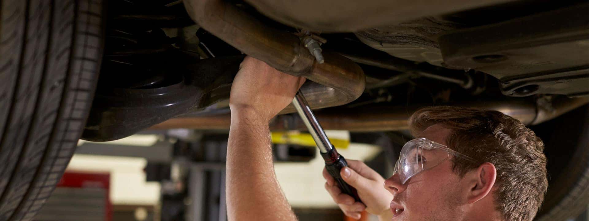 technician servicing an exhaust pipe on a car