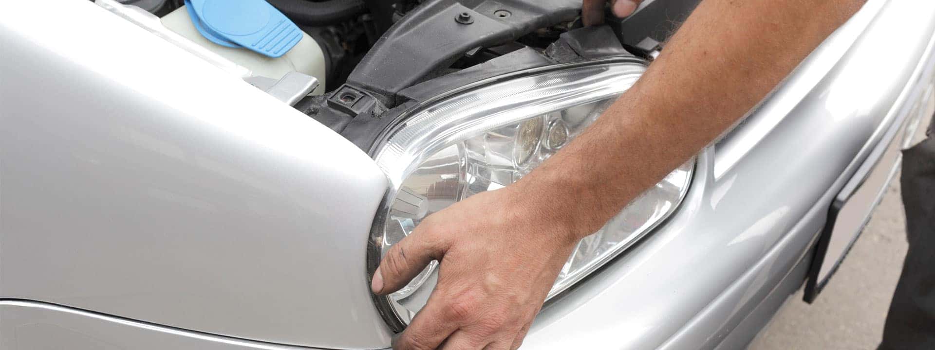 technician replacing a headlight on a car