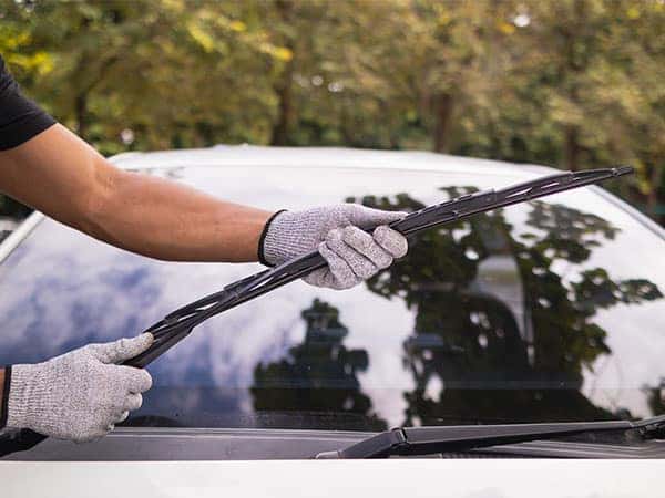 technician replacing windshield wipers on a car