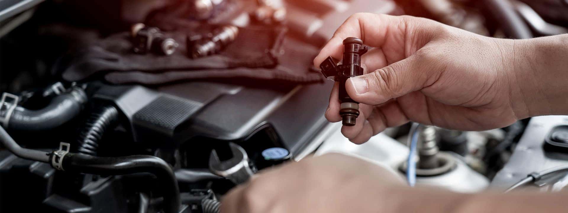 technician servicing a fuel injector on a car