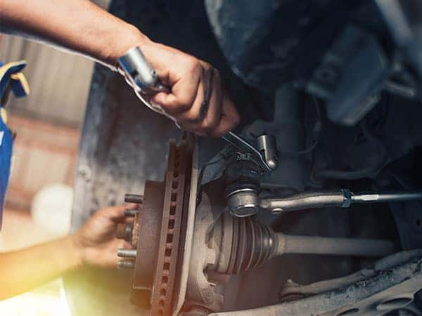 technician repairing the suspension of a car with a spanner
