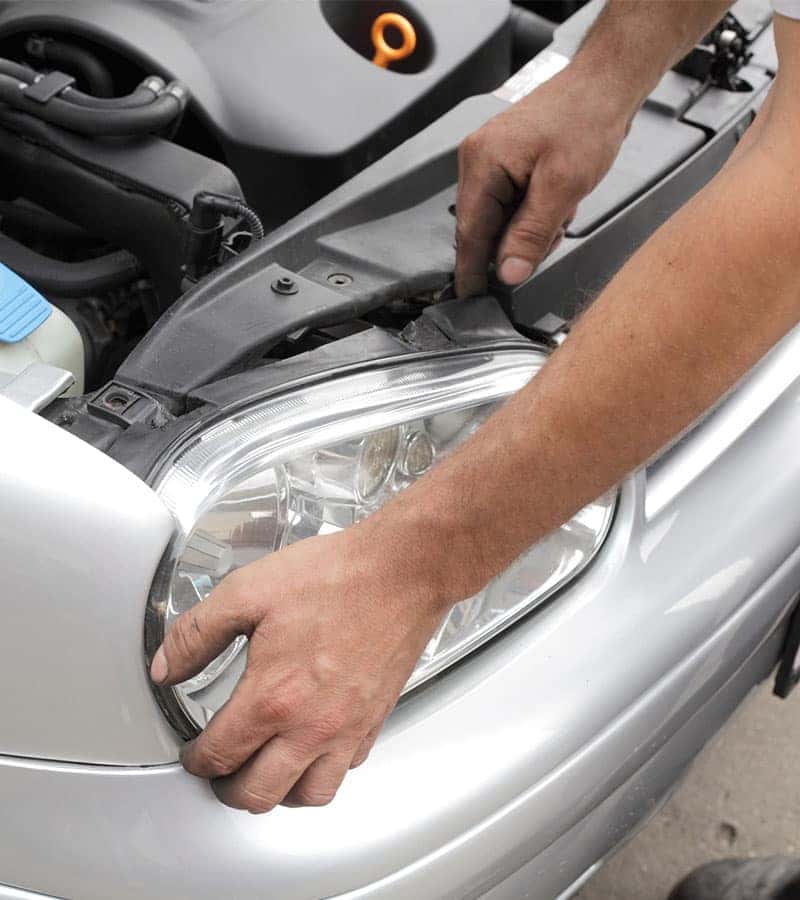 technician replacing a headlight on a car