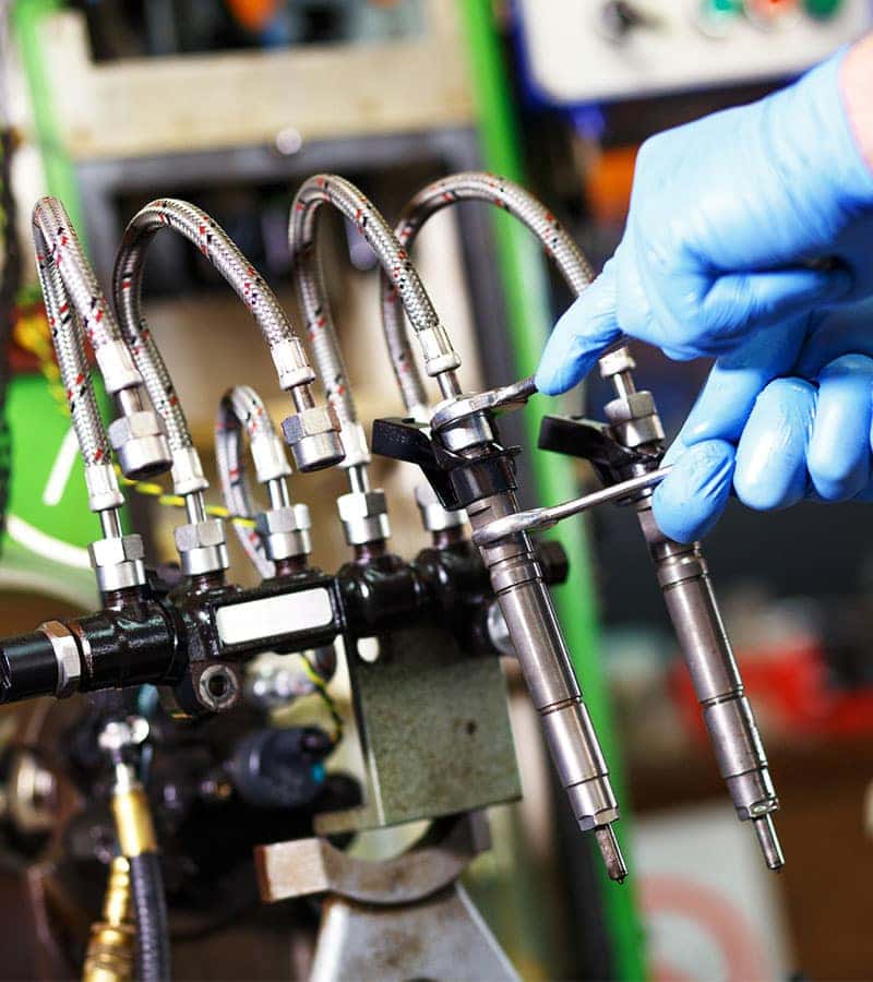 technician servicing a fuel injector on a car