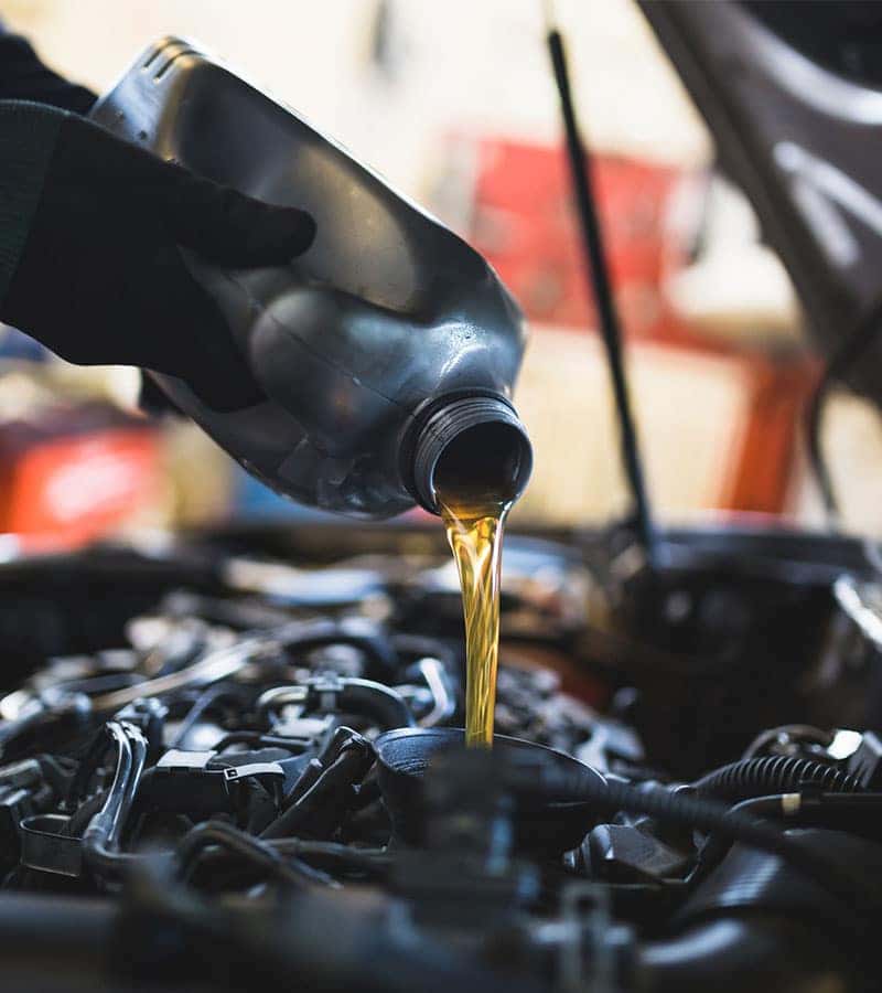 technician performing an oil change to a car