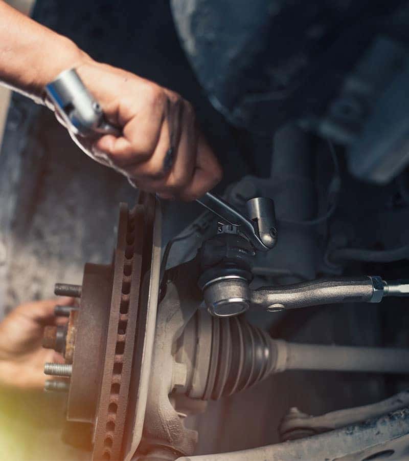 technician repairing the suspension of a car with a spanner