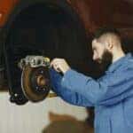 man fixing car brakes