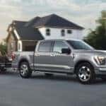 silver ford f150 towing a forklift in a new development neighborhood