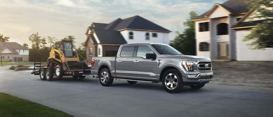 silver ford f150 towing a forklift in a new development neighborhood