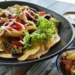 plate of nachos with toppings on the side